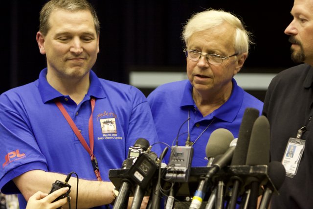 Press Conference with Three Men in Blue Shirts