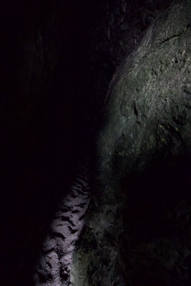 Dark Cave Passage with Sandy Floor and Rocky Wall