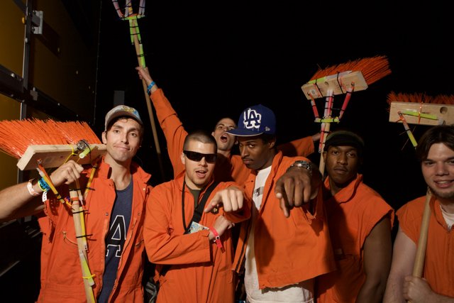 Men in Orange Outfits Holding Broom Sticks
