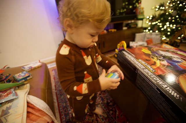Toddler Opening Christmas Presents by Lit Tree
