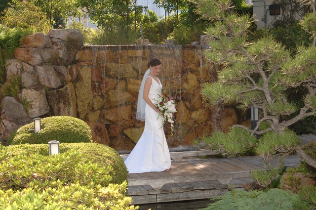 Bride Poses Before Cascading Waterfall in Japanese Garden