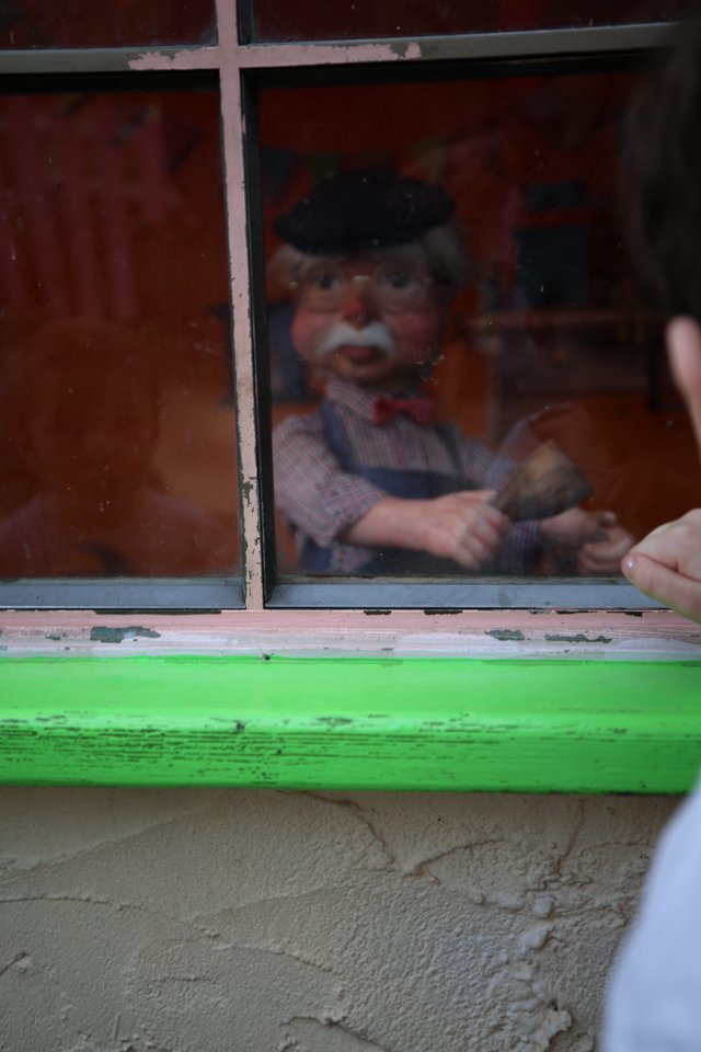 Vintage Puppet Display Behind Weathered Green Window