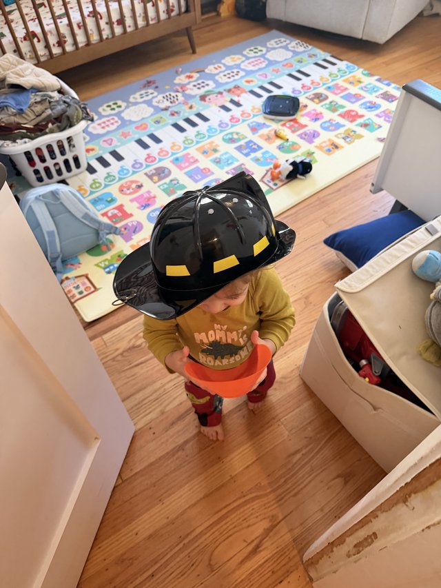 Toddler Playing Firefighter at Home with Toy Helmet