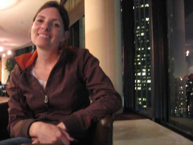 Smiling Woman at High-Rise Bar with City Lights