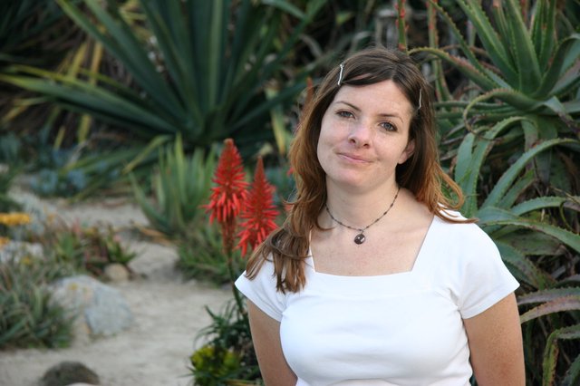 Woman Smiling Amid Desert Succulents and Aloe Blooms