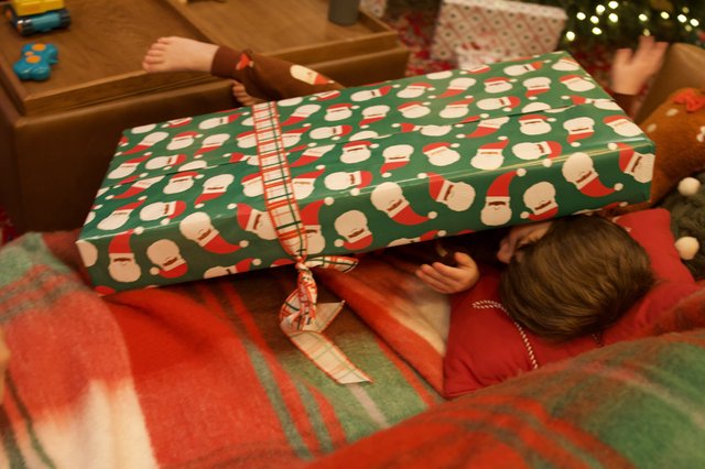 Child Opening Christmas Present with Santa Wrapping Paper