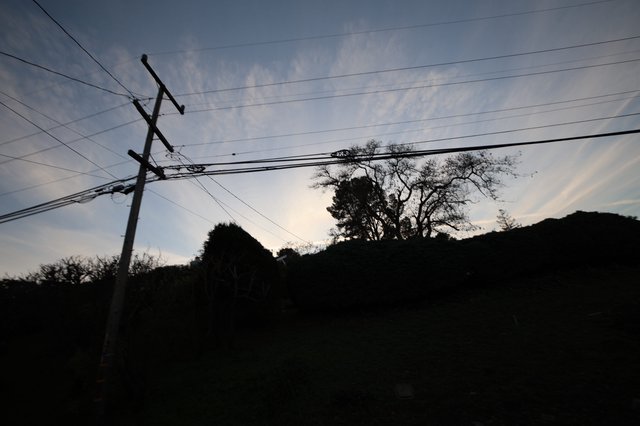Silhouetted Power Lines at Dusk Over Rural Hillside