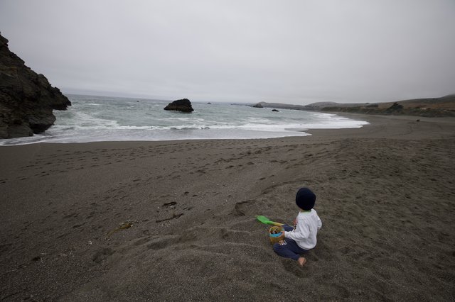 Child Playing Alone on a Rugged Coastal Beach