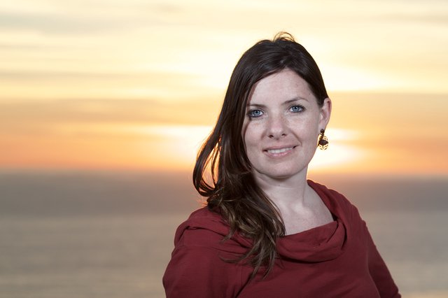 Woman Smiling at Golden Sunset Over Water