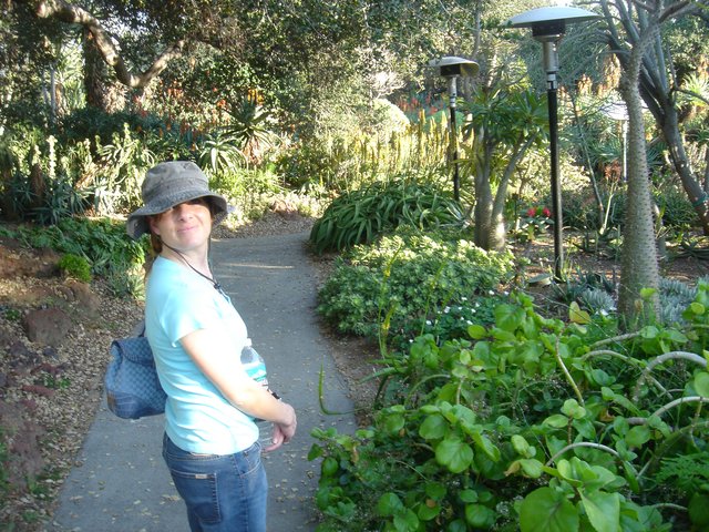 Woman Smiling on Lush Botanical Garden Pathway