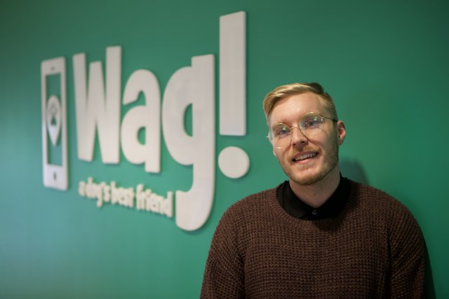 Stylish Man in Glasses Poses in Front of WAG Logo
