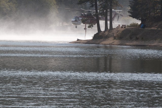 Helicopter Fighting Wildfire by Spraying Water onto Lake