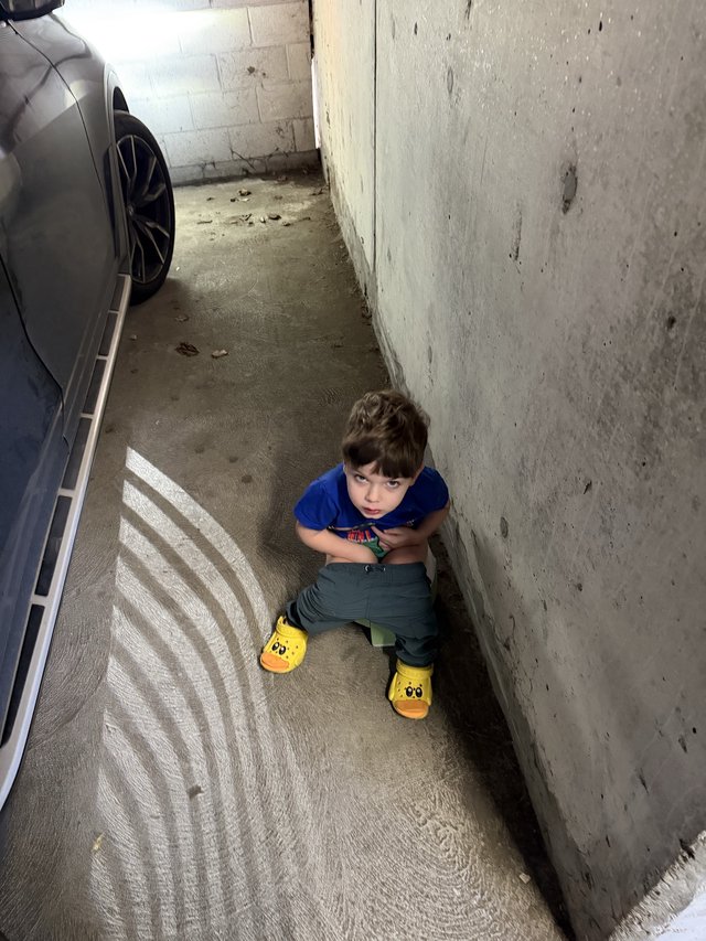 Young Child Sitting in Narrow Parking Garage Space