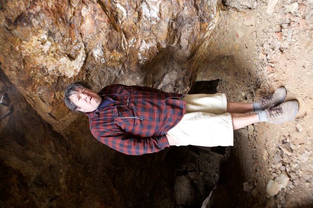 Man Standing Inside a Rocky Cave Entrance