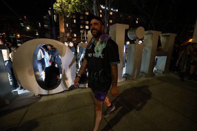 Festival Goer Poses at Wobbleland Sign at Night