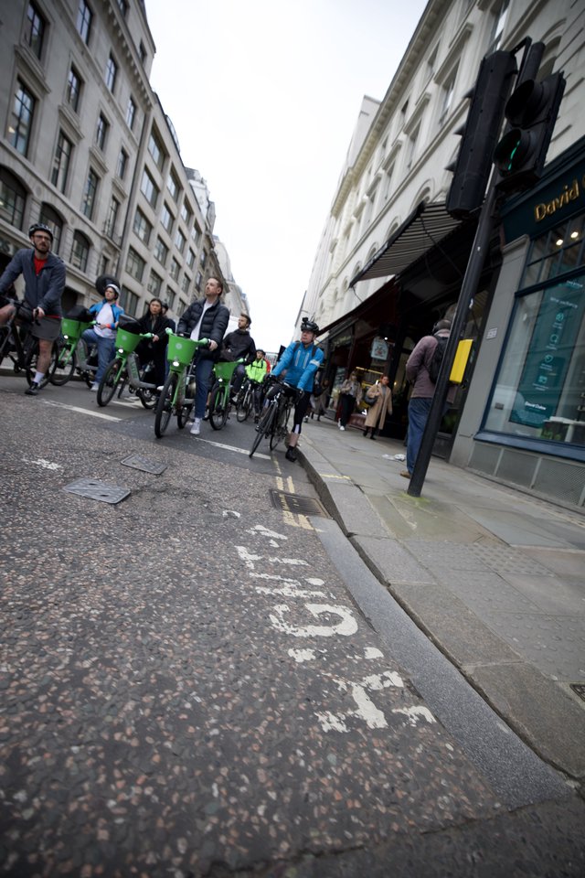 Bike Share Cyclists Riding Through London Shopping Street
