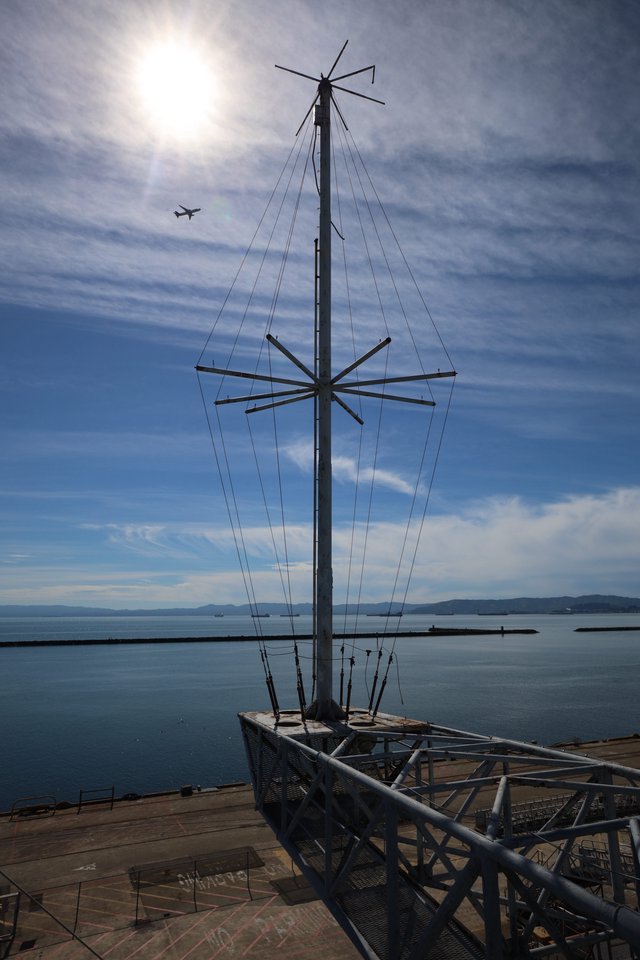 Silhouetted Ship Mast Against Coastal Skyline