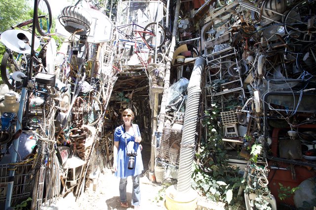 Woman Photographer Dwarfed by Cathedral of Junk Austin