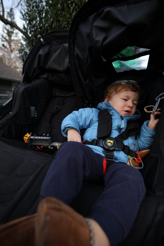Unhappy Toddler Secured in Black Jogging Stroller