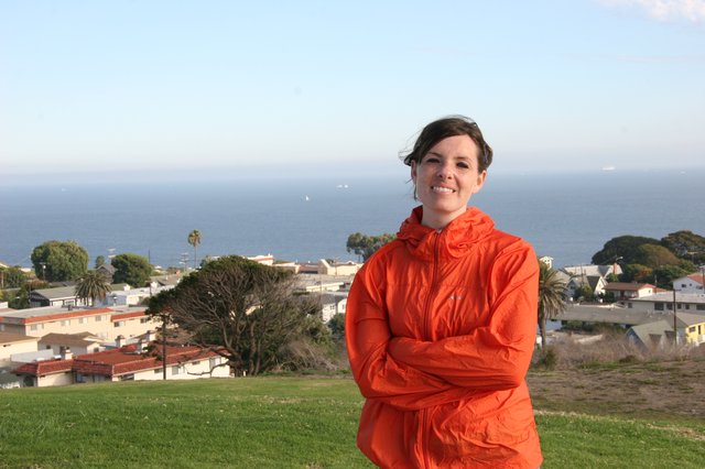 Woman in Orange Jacket Overlooking Coastal Town