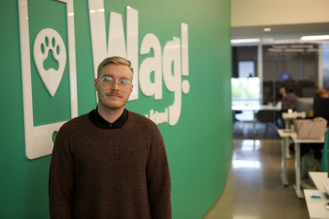 Sweater-clad man poses before wag logo