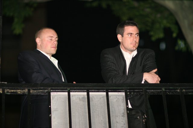 Two Men Standing on Balcony in Formal Attire