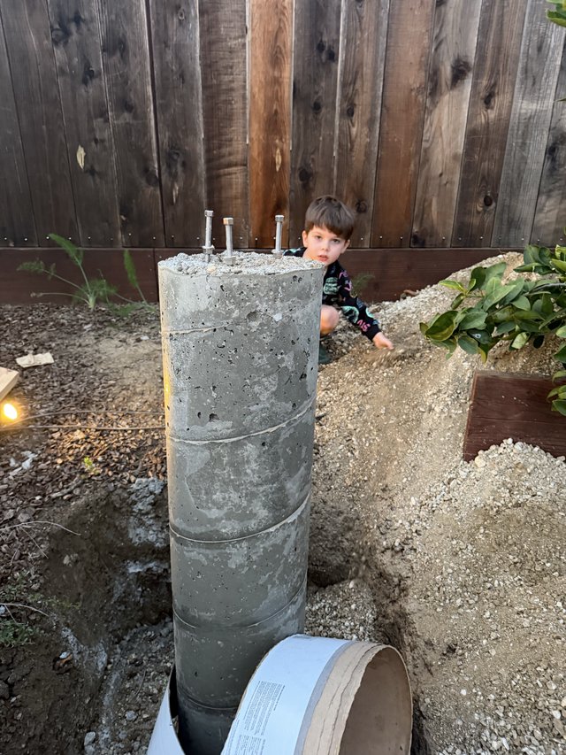 Young Boy Explores Concrete Pier Foundation in Backyard