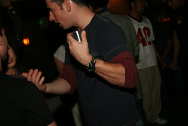 Black-shirted man checks watch at the club