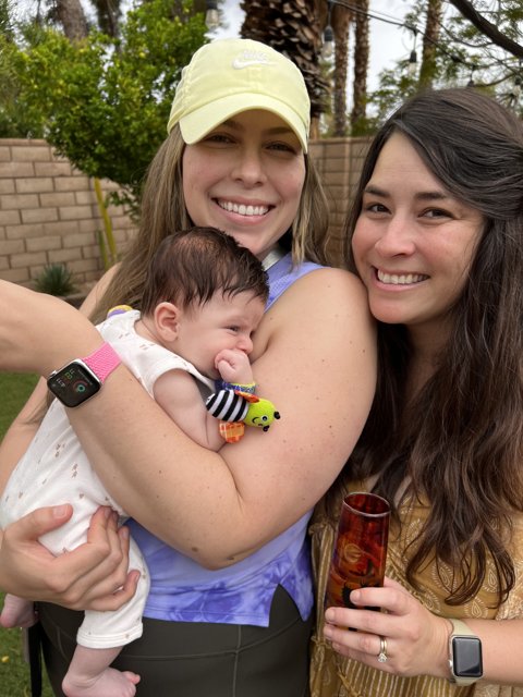 Two Women Bask in the Joy of Holding a Newborn Baby Outdoors