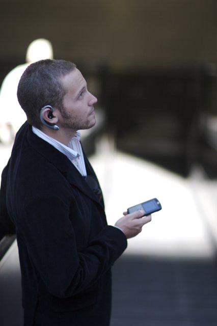 Businessman using mobile phone Caption: A man dressed in a suit and tie uses his mobile phone to text while on a break from a consumer electronics shoot in 2006.