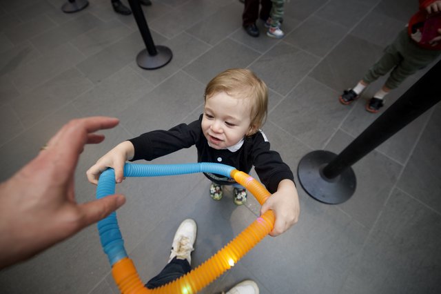 Toddler Playing with Colorful Tubes at Baby Rave Event