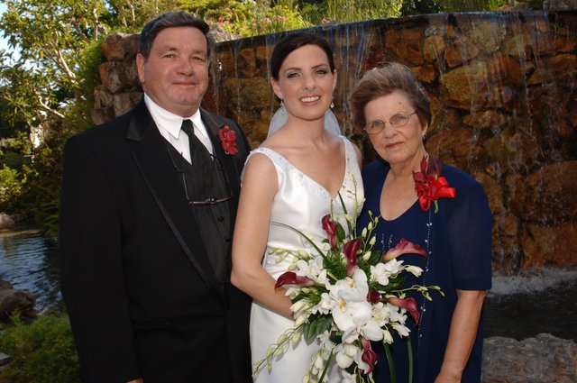Bride Poses With Parents at Garden Wedding