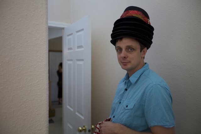 Hat-wearing man stands at door