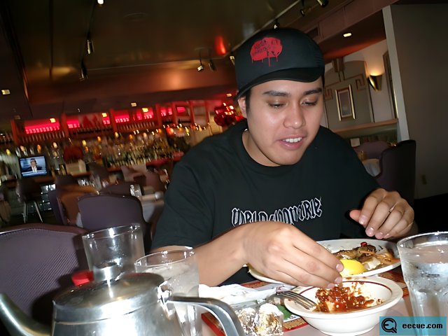 A Man in Black Hat Enjoying a Meal at a Restaurant