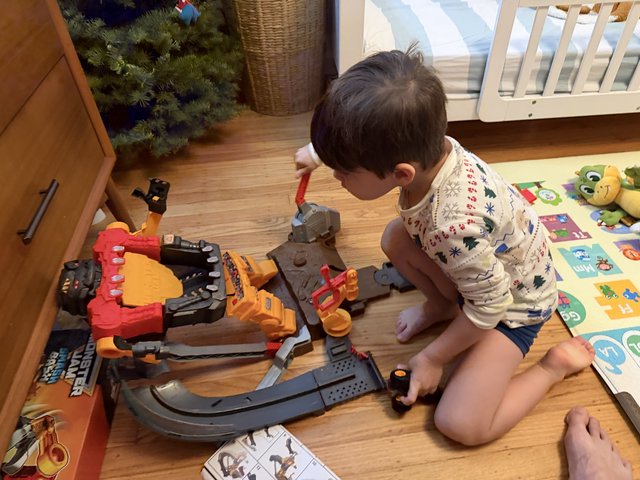 Young Boy Playing with Monster Truck Toy Set at Home
