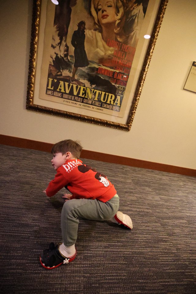Child Playing Near Classic Film Poster in Lobby