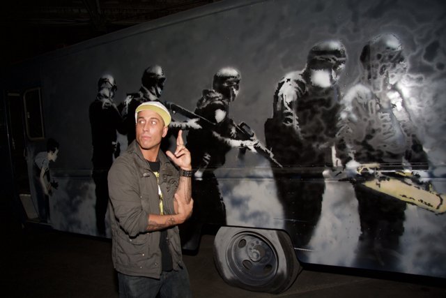 Gun-wielding Man in Front of a Mural
