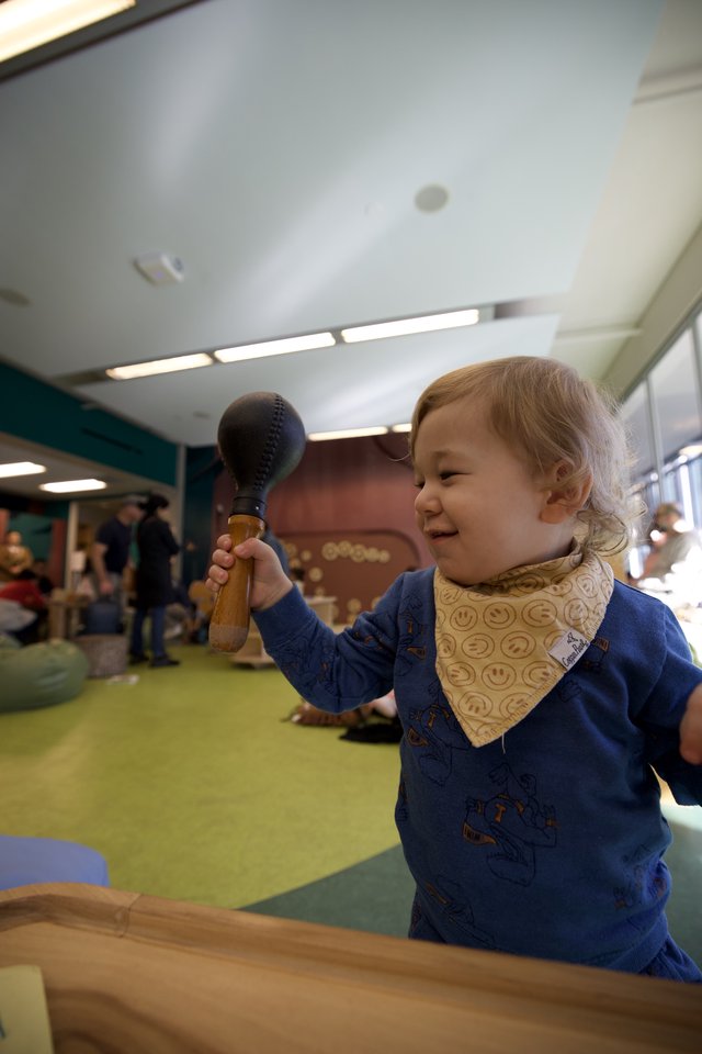 Joyful Toddler Playing with Wooden Toy at Children's Museum