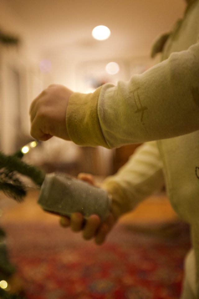 Hands Hanging Glass Ornament on Christmas Tree