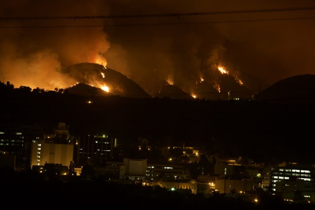 Flames Engulf Hillside Above Cityscape