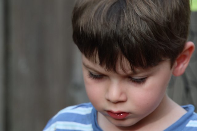Young Child in Contemplative Moment, Blue Striped Shirt