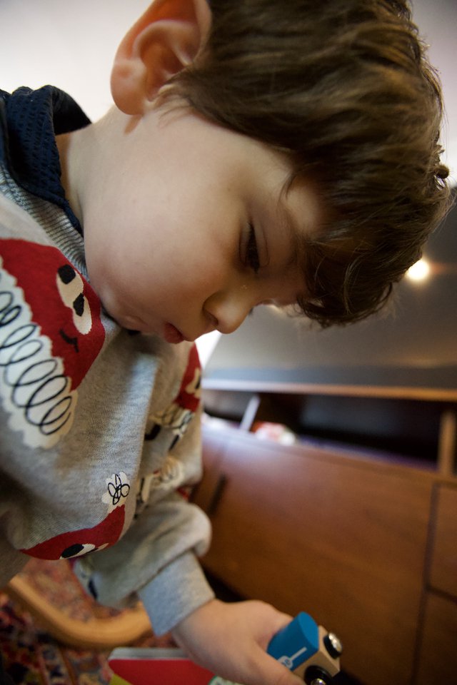 Young Child Focused on Play with Wooden Train Set