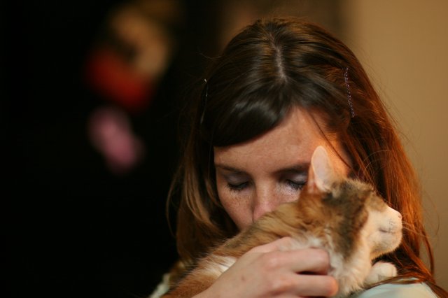Tender Moment: Woman Nuzzles Orange Tabby Kitten