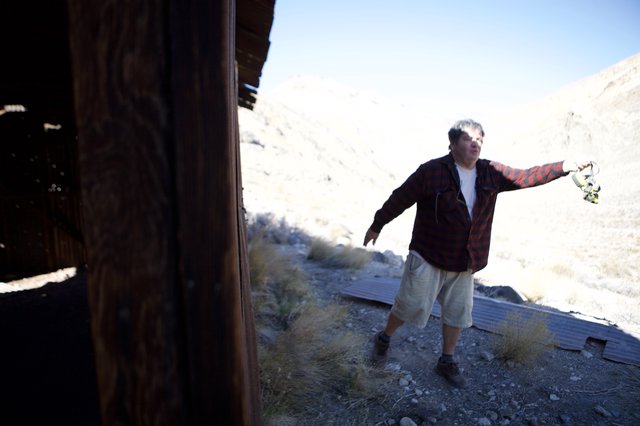 Explorer Holds Headlamp at Desert Ghost Town Ruins