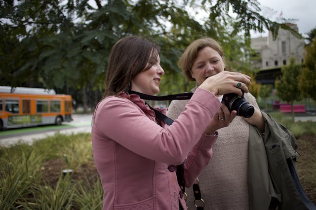 Two Women Sharing Photos on Olympus Camera Outdoors