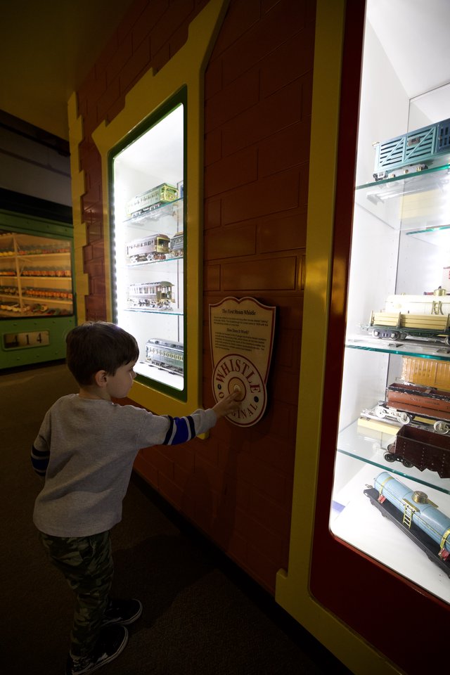Young Boy Explores Interactive Train Whistle Exhibit at Museum