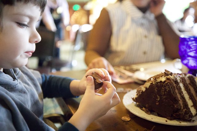 Young Boy Enjoying Chocolate Cake at Family Gathering