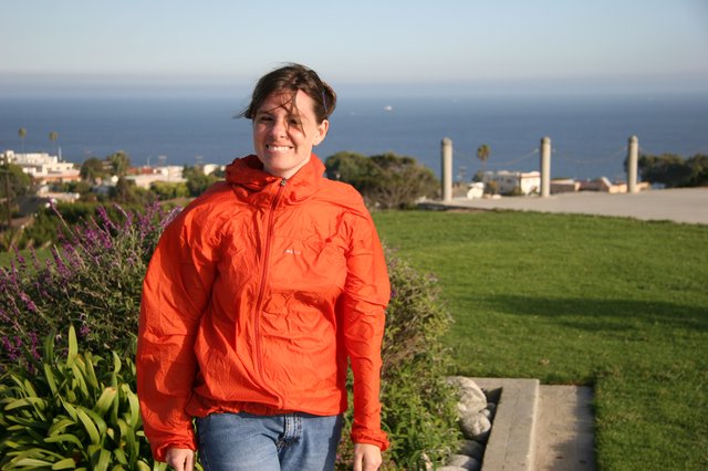 Smiling Woman in Orange Jacket by the Sea