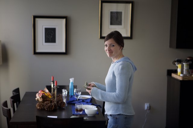 Woman Counting Cash at Home Dining Table