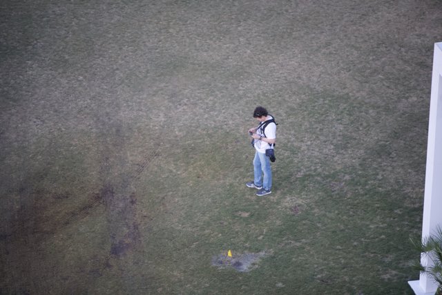 Checking his phone on the grass